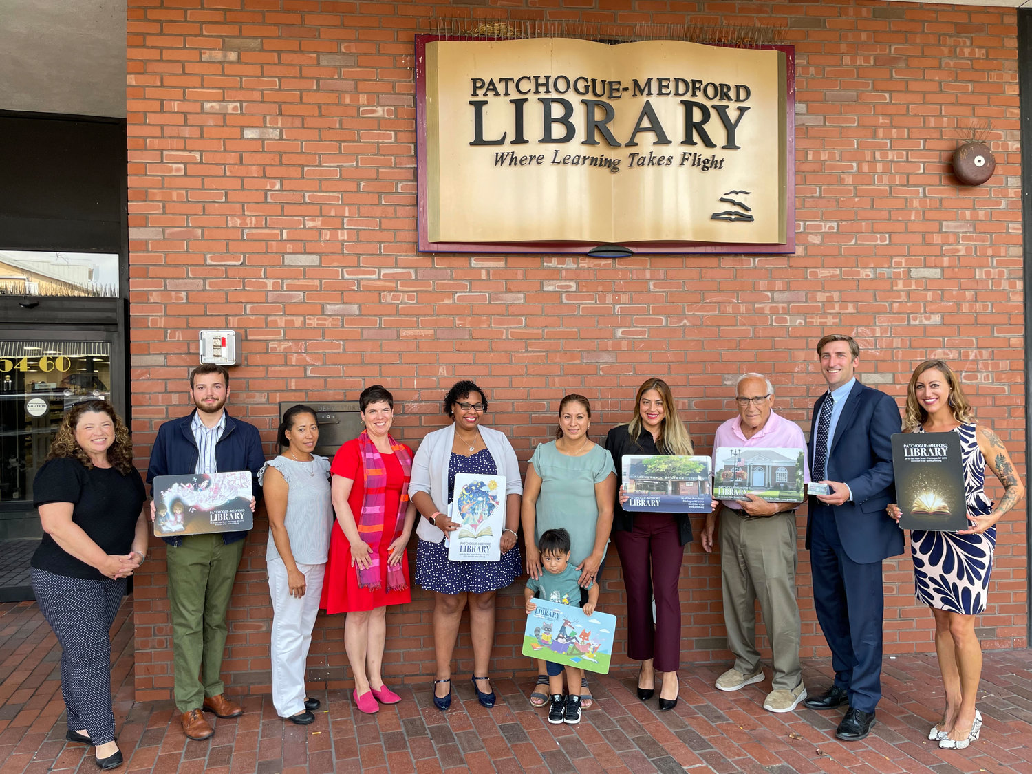 L-R: Library director Danielle Paisley, library trainee Joshua Tanski, Pat-Med Library community service worker Juana Shellman, Pat-Med Library assistant director Jennifer Bollerman, head of community access to resources and education Lissetty Thomas, community member Lurdes Balbuca and her son Jaziel Hernandez, 2, Patchogue Village trustee Lizbeth Carrillo, Patchogue mayor Paul Pontieri, community advocate Ryan McGarry, head of public services Michele Cayea.